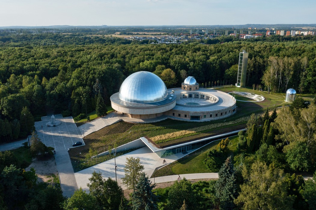 Na zdjęciu widzimy zmodernizowany kompleks budynków Planetarium w otoczeniu roślinności parkowej oraz panoramę Siemianowic Śląskich. 