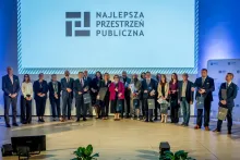 Zdjęcie grupowe laureatów konkursu na najlepszą przestrzeń publiczna województwa śląskiego, na tle slajdu z logiem konkursu. 