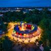 cylindryczna bryła obiektu widzianego nocą z atrium i centralnie zlokalizowaną fontanną. Wielobarwne oświetlenie iluminacyjne nadaje obiektowi wpisanemu w otoczenie malowniczego parku niepowtarzalny i oryginalny charakter.