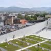 Kadr z drona. Na pierwszym planie dwa budynki z dziedzińcem oraz terenami zielonymi. W tle panorama Bielska-Białej. Fragmenty zabytkowych zabudowań oraz góry. 