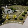 Widok z lotu ptaka na park z pomnikiem oraz amfiteatralnie ukształtowaną zielenią. Centralnie znajduje się biały monument z flagami, wokół którego rozmieszczono symetryczne rabaty z niskimi krzewami. Po lewej stronie widoczny jest okrągły plac przypominający scenę, a całość otoczona jest przez gęsty las. Przez środek biegnie główna aleja, z której odchodzą mniejsze ścieżki.