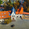 Widok z lotu ptaka na część wschodnią połączonych zabudowań zamku Piastowskiego w Raciborzu – w centralnej części zdjęcia od lewej: dom książęcy, gotycka kaplica, budynek bramny i baszta. Nad zabudowaniami w tle zieleń. Poniżej zabudowań dziedziniec ze studnią i drzewem.