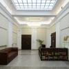 spinPLACE, centrum kreatywności i coworkingu - hall wejściowy. Posadzka z lastriko, ściany z historycznym detalem. Sufit z dużym przeszkleniem wprowadzającym światło dzienne. W pomieszczeniu drewniana lada recepcyjna i skórzana kanapa. W tle drzwi do innych pomieszczeń.