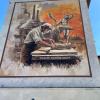 Mural na elewacji kamienicy przedstawiający rzeźbiarza przy pracy nad rzeźbą chłopca z łabędziem, w tle panorama huty z kominami i pomarańczowe niebo. Napis: „THEODOR ERDMANN KALIDE"