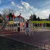 Widok na część sprawnościową placu zabaw z elementami do wspinania, przechodzenia i aktywności ruchowej. Obiekt jest ogrodzony i dostosowany do bezpiecznego użytkowania przez dzieci oraz opiekunów.