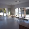 Widok na jasną, przestronną salę lekcyjną w szkole w Iłownicy z dużymi oknami, wychodzącymi na teren wokół. 