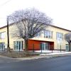 Nowoczesny dwukondygnacyjny budynek dydaktyczny po rozbudowie. Jasna elewacja, kontrastująca cegła wokół dużych okien i drzwi wejściowych na parterze.